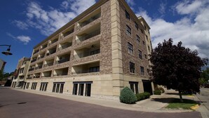 A multi-story building with a brick facade, multiple balconies, and a clear sky. - Luxury condo in the heart of downtown Grand Haven. (Grand Haven)