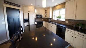 A modern kitchen with white cabinets, a black countertop, and a central island. - Luxury condo in the heart of downtown Grand Haven. (Grand Haven)
