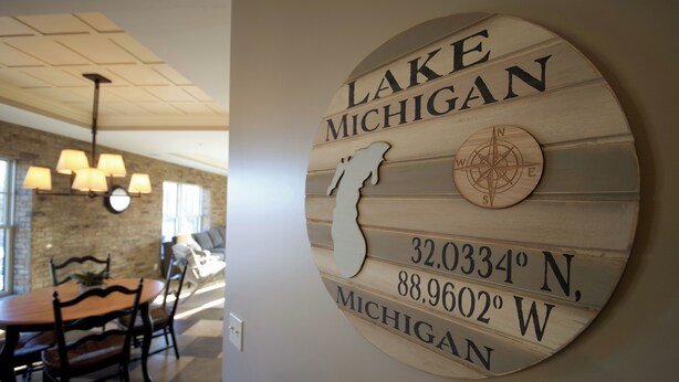 A wall-mounted sign with the text "LAKE MICHIGAN" and coordinates "32.0334° N, 88.9602° W, MICHIGAN". - Luxury condo in the heart of downtown Grand Haven. (Grand Haven)