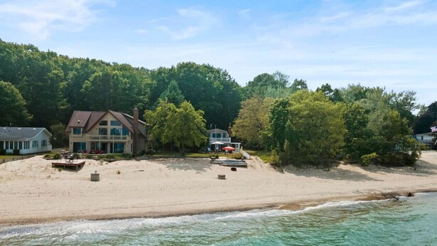 A beachfront property with a large house, a smaller building, and a sandy beach.