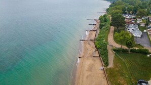 Une vue aérienne d’une zone côtière, avec une plage, des maisons et une vue dégagée sur l’océan.