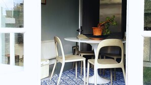 Un coin repas comprenant une table ronde, quatre chaises, une plante en pot et un radiateur.