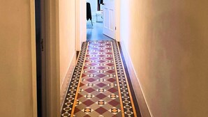 Un couloir au sol décoré de motifs et une porte au fond.