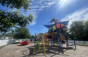 A playground with a climbing structure, slides, and a red bean bag chair.