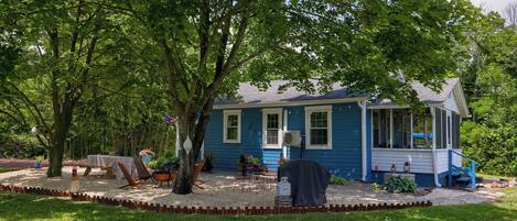 A blue house with a covered porch, surrounded by a well-maintained garden and trees.
