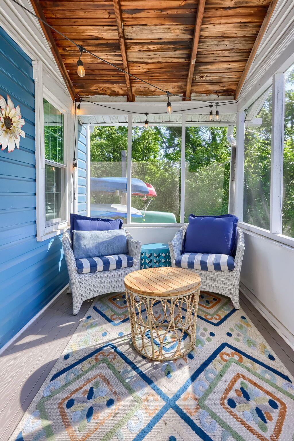 A covered porch with wicker furniture and a patterned rug.