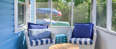 A covered porch with wicker furniture and a patterned rug.
