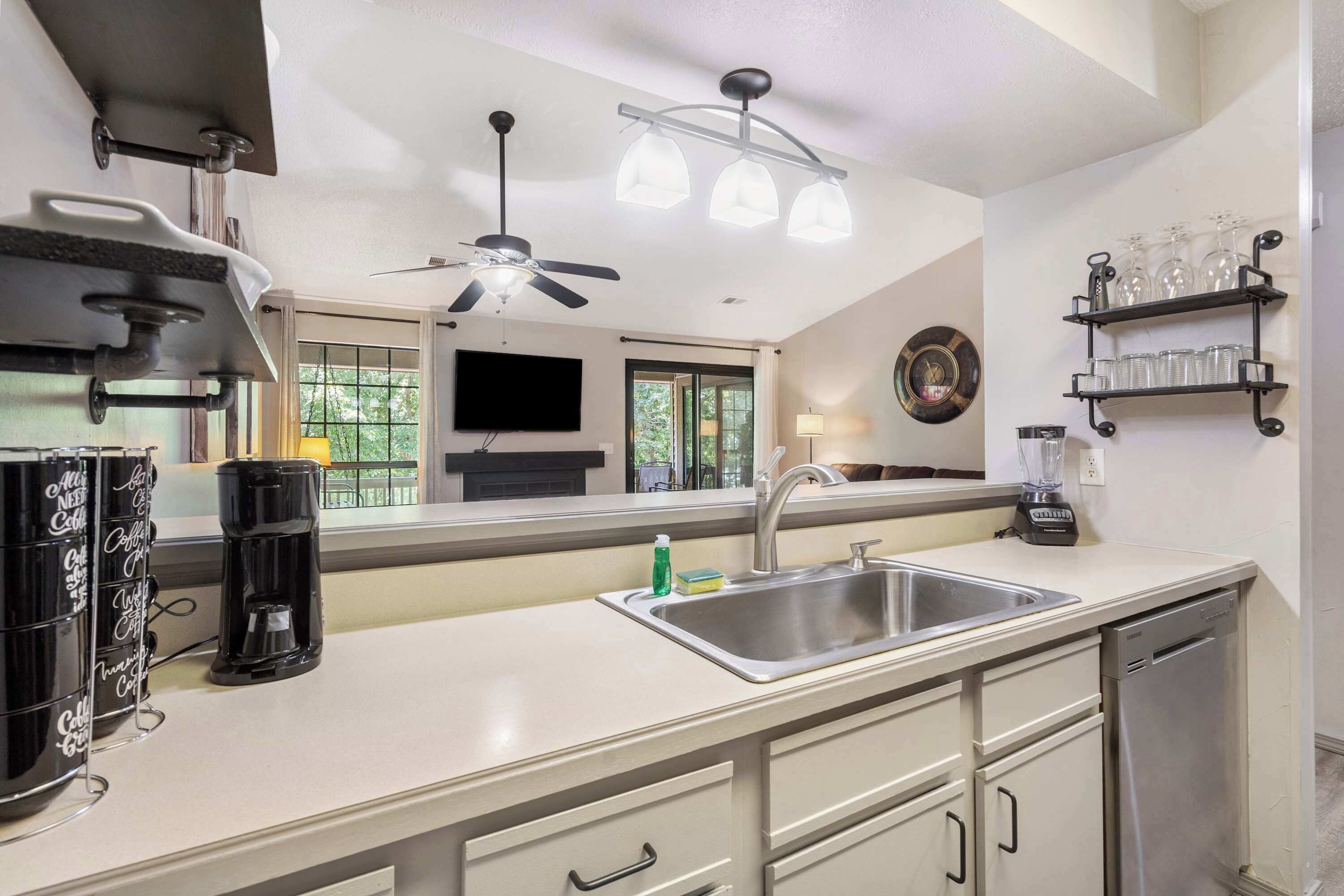 A modern kitchen with a sink, coffee maker, and a ceiling fan.