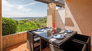 A balcony with a table set for two, overlooking a scenic landscape.