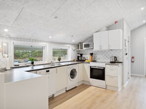 A modern kitchen with white cabinetry, a built-in washing machine, a microwave, and a coffee maker. - "Keke" - 2.5km from the sea by Interhome (Rømø)