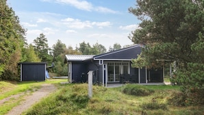 Een modern huis met een ruime patio, een garage en een kleine schuur.