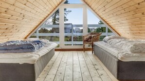 A triangular attic bedroom with two beds, a wicker chair, and a view through a glass door. - "Antero" - 4km from the sea by Interhome (Rømø)