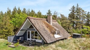 A thatched-roof house with a chimney, a dining area with outdoor seating, and a view of the surrounding forest. - "Antero" - 4km from the sea by Interhome (Rømø)