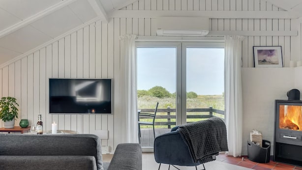 Una sala de estar moderna con televisor, chimenea y vistas al exterior.