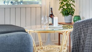 Una mesa de vidrio con una botella y una vela, una planta en maceta y una lámpara en una habitación con paneles blancos.