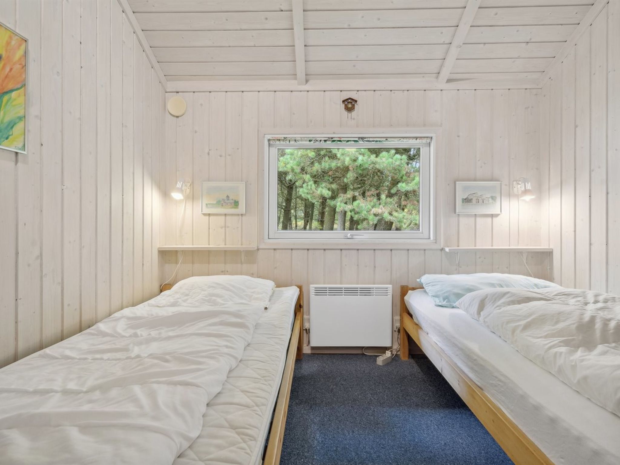 Une cabine équipée de deux lits simples, d’une fenêtre donnant sur la forêt et d’un petit radiateur placé sous la fenêtre.