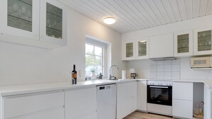 Una cocina moderna con armarios blancos, horno integrado y ventana que proporciona luz natural.