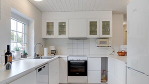 Una cocina moderna con armarios blancos, un horno Bosch y una cafetera.