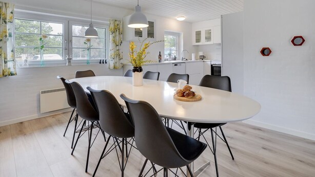 Un comedor moderno con una mesa redonda, sillas negras y un florero con flores.