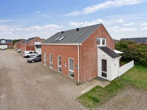Eine Reihe roter Backsteingebäude mit einem Schotterweg und abgestellten Autos.