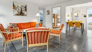 Un soggiorno moderno con un divano, poltrone, un tavolo da pranzo e un quadro appeso al muro.