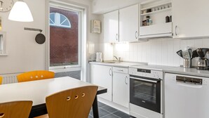 Una cucina moderna con mobili bianchi, forno integrato e macchina per il caffè.