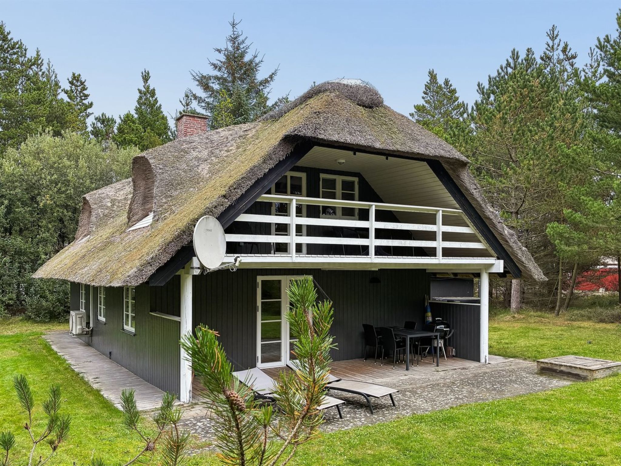 A thatched-roof house with a covered patio and outdoor seating area.
