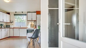 A modern kitchen with white cabinets, a dining area with a table and chairs, and a large sliding glass door leading to a balcony. - "Toralf" - 3.5km from the sea by Interhome (Rømø)