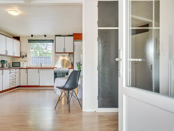 A modern kitchen with white cabinets, a dining area with a table and chairs, and a large sliding glass door leading to a balcony.