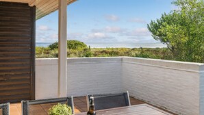 A wooden table with chairs and a bottle of beer on a balcony overlooking a body of water. - "Toralf" - 3.5km from the sea by Interhome (Rømø)