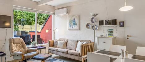 Ein modernes Wohnzimmer mit einer Couch, einem Sessel und einem Esstisch.