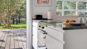 A modern kitchen with white cabinetry, a stainless steel countertop, and a large window overlooking a deck. - "Tora" - 3km from the sea by Interhome (Rømø)