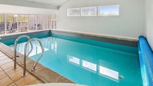 An indoor swimming pool with clear blue water, a tiled floor, and a view of the outdoors through large windows. - "Tora" - 3km from the sea by Interhome (Rømø)