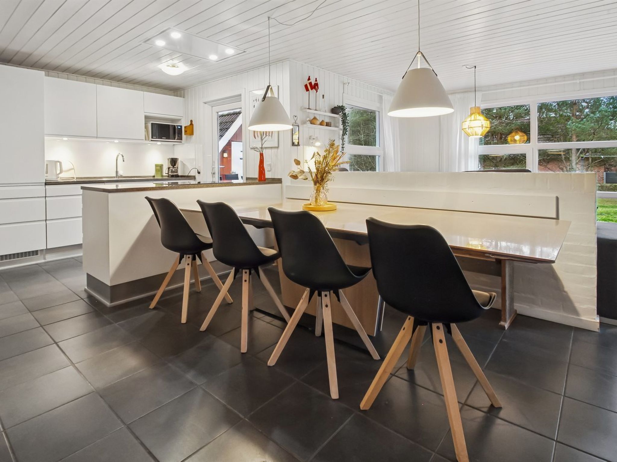 Una cocina moderna con una isla central, sillas negras e iluminación colgante.