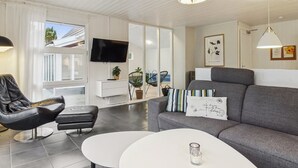 A modern living room with a grey sofa, a black leather chair, a white coffee table, and a flat-screen TV mounted on the wall. - "Tora" - 3km from the sea by Interhome (Rømø)