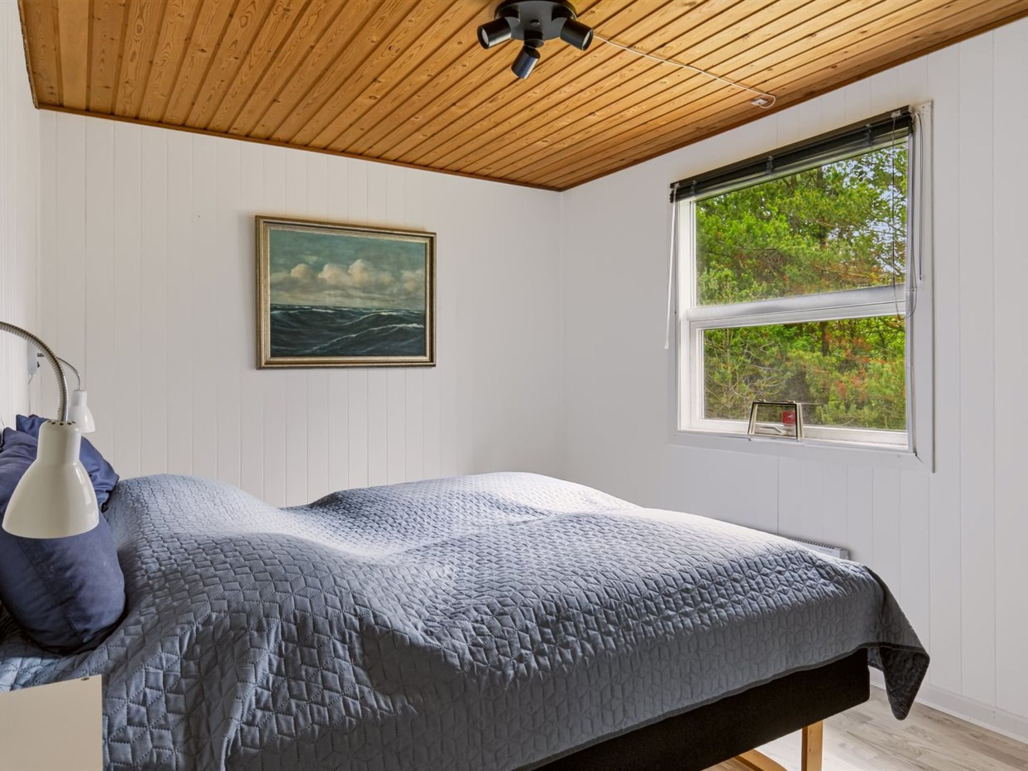 Ein Schlafzimmer mit Bett, einem Gemälde, einem Fenster und einem Deckenventilator.
