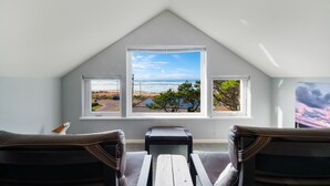 A room with a view of the beach and ocean through a large window, a wooden table, and two leather chairs. - The Cachalot MCA# 50330- Oceanview, 1/4 block to beach, Dogs OK, Game room (Manzanita)