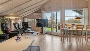 A spacious living area with a high ceiling, a large flat-screen TV, leather recliners, a dining table with chairs, and a view of the outdoors through large windows. - "Vivan" - 3.8km from the sea by Interhome (Rømø)