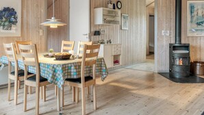 A cozy room with a wooden interior, a dining table with chairs, a hanging light fixture, a stove, and a door leading to another room. - "Vivan" - 3.8km from the sea by Interhome (Rømø)