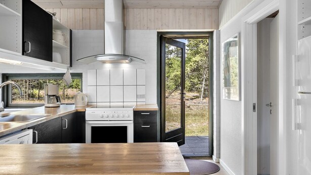 Una cocina moderna con encimera de madera, electrodomésticos de acero inoxidable y vistas al exterior a través de un ventanal.