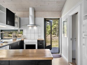 Una cocina moderna con encimera de madera, electrodomésticos de acero inoxidable y vistas al exterior a través de un ventanal.