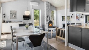 Una cocina moderna con estufa de leña empotrada, paredes de ladrillo blanco y una gran mesa de comedor con sillas.