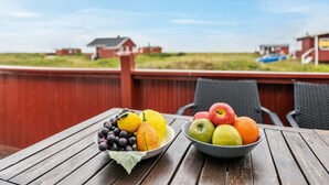 Ein Holztisch mit zwei Fruchtschalen auf einer Terrasse.