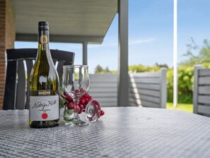 A bottle of Notte's Hill Chardonnay 2019 on a table with a glass and grapes.