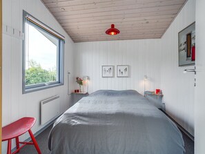 A bedroom with a large bed, a window, a red chair, and two bedside tables with lamps.