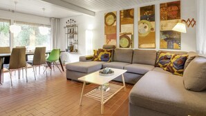 Un salon moderne avec un canapé gris, une table basse blanche et un coin repas comprenant des chaises et une table.