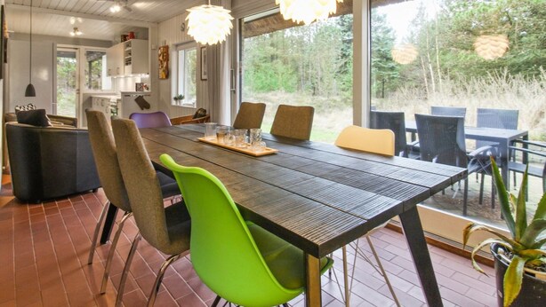 Un espace de salle à manger moderne, doté d’une longue table, de nombreuses chaises et de luminaires suspendus.