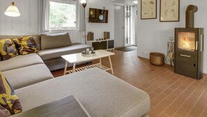 Un salon chaleureux avec un canapé, une table basse, une cheminée et des reproductions encadrées de motifs botaniques accrochées au mur.
