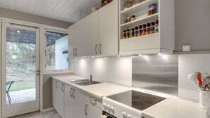 Une cuisine moderne avec des armoires blanches, une cuisinière en acier inoxydable et un four encastré.