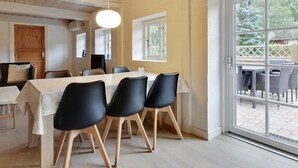 Un comedor moderno con una mesa grande, sillas negras y vistas al patio exterior.